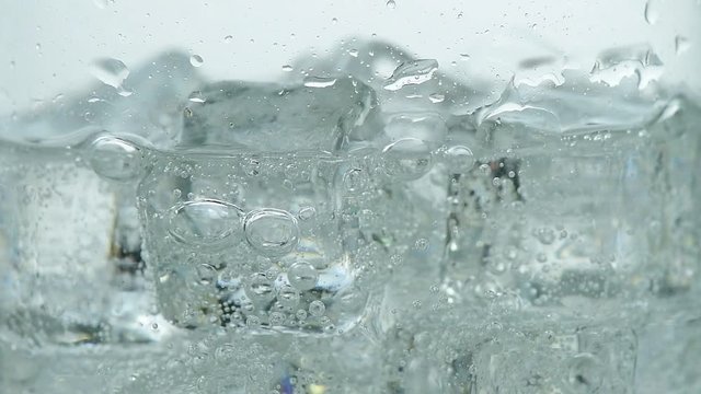 Pouring soda water with ice and bubbles in the glass