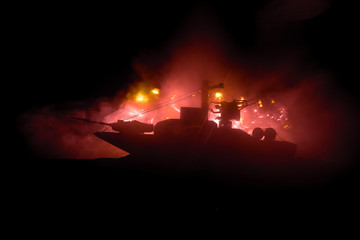 Sea battle scene. Silhouette of military war ship on dark foggy toned sky background. Explosion and...