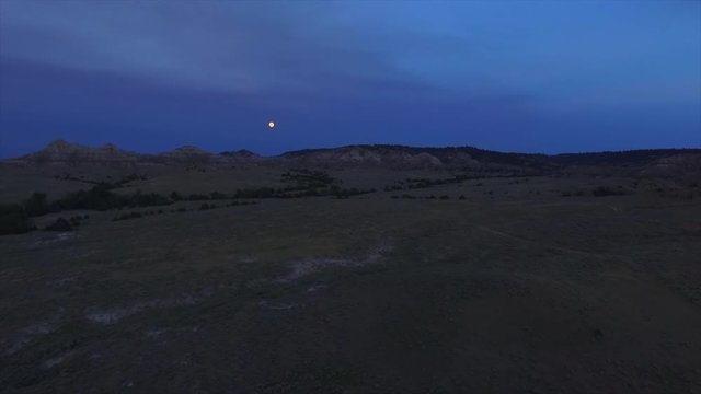 A slow cinematic drone shot panning towards the moon at dusk.