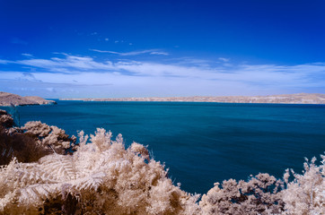 View of blue waters across a bay under a bright blue sky with some clouds