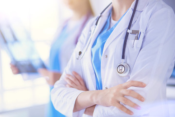 Close up shoot of doctor's crossed hands and colleague with x-ray on the background.