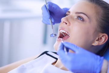 Young Female patient with open mouth examining dental inspection at dentist office.