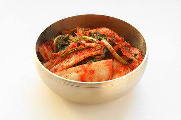 The most famous Korean food Kimchi(geotjeori, fresh vegetable salad) in traditional brassware. Isolated on white background. 