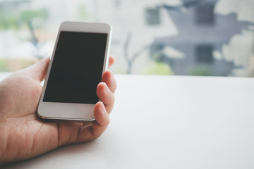 Mockup image of woman hand holding white mobile phone with blank screen black colour smartphone