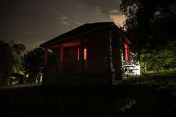 Mountain night landscape of building at forest at night with moon or vintage country house at night with clouds and stars. Summer night.