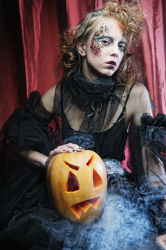 Halloween witch with  carved pumpkin over red  background. 
