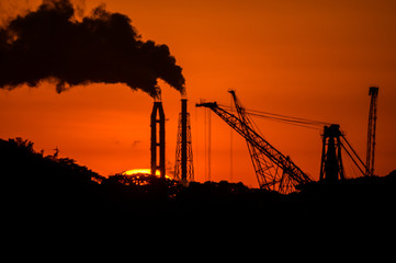 日没の工場の煙突と煙