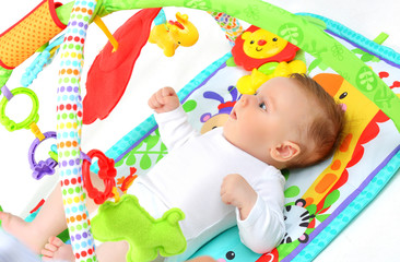 Fototapeta na wymiar 4 month old Baby is lying on the playing Mat. The concept of development of the newborn.