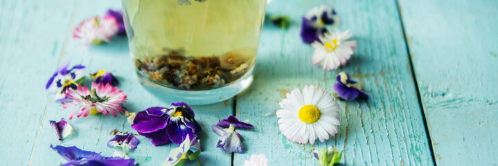 Cup of tea with chamomile flowers on rustic wooden background