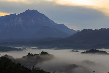 Beautiful sunrise landscape scenery with sunlight and fog and Mount Kinabalu as background in Guakon, Sabah, Malaysia