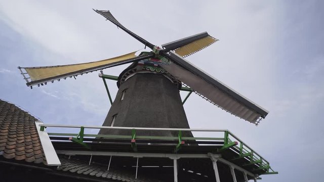 Panoram under working windmill. Bottom view rotating blades typical holland windmill at grey sky background. Dutch village Zaanse Schans open-air museum in the Netherlands