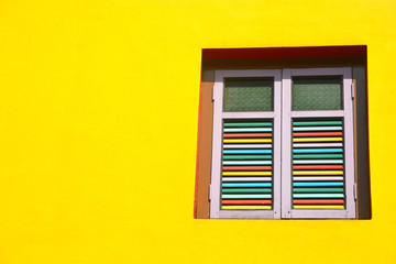 Bright colored house, yellow wall with wooden windows in Little India, Singapore.