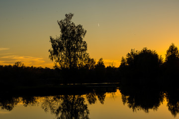An airplane leaves a vapor trail as it flies over a lake in Southern Germany at sunset