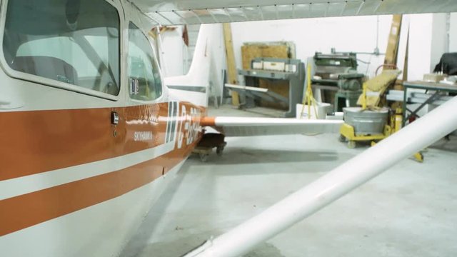 Slow motion camera pan right to left  showing shop floor with Cessna airplane missing engine. .