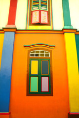Bright colored house, orange wall with wooden windows in Little India, Singapore.