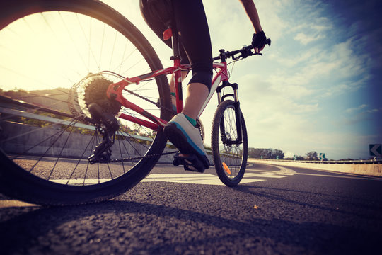 Woman cyclist legs riding Mountain Bike on highway