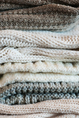 A stack of textured knitted things of light colors. The concept of comfort, warmth.