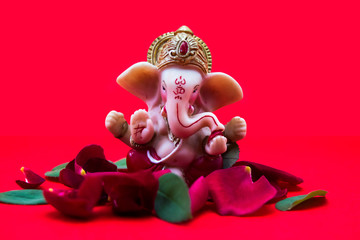 Lord Ganesha Idol with rose petals on red background