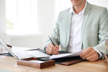 Male notary signing document at table in office, closeup