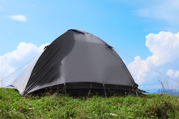 Small camping tent in mountains on sunny day