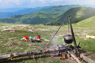 Cooking breakfast on fire in mountains. Camping season