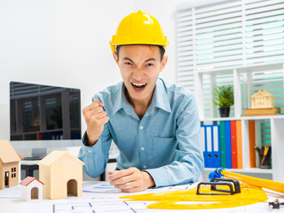 Young Asian man architect working at working desk about his housing project.