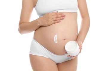 Pregnant woman applying body cream on belly against white background, closeup