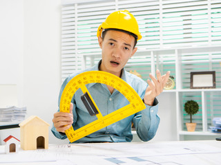Young Asian man architect working at working desk about his housing project.