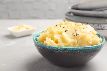 Bowl with tasty mashed potato on gray table