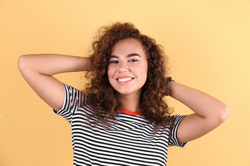 Portrait of young laughing African-American woman on color background