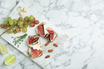 Sandwiches with ripe figs and delicious products on marble table, top view. Space for text