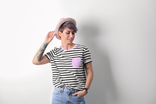 Trendy young woman with tattoos on white background