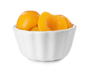 Bowl with halves of canned peaches on white background
