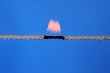 Burning rope at breaking point on color background