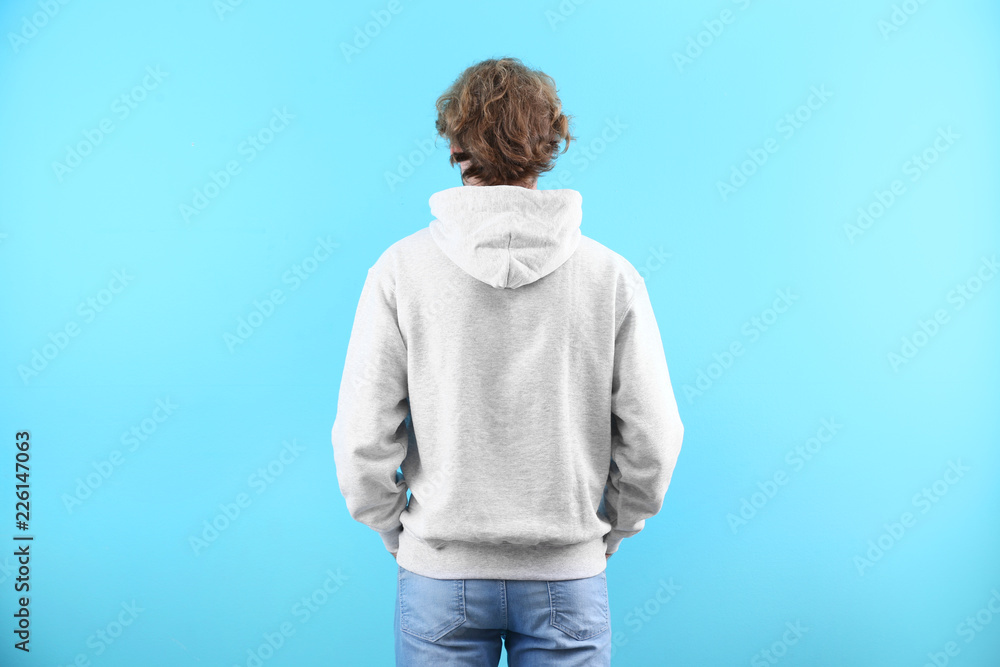 Wall mural Man in hoodie sweater on color background. Space for design