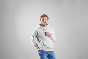 Portrait of man in hoodie sweater on light background. Space for design