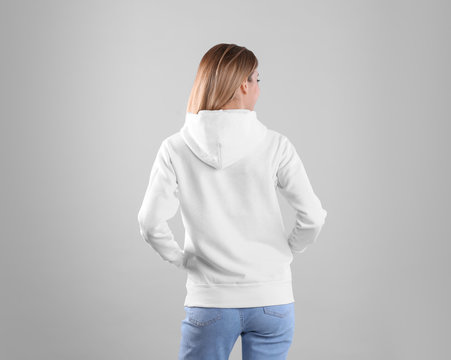 Woman in hoodie sweater on light background. Space for design