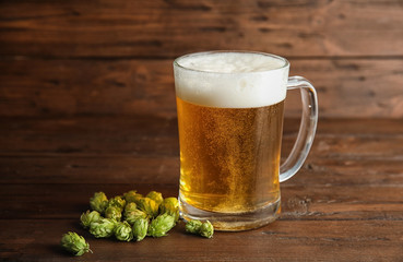 Composition with tasty beer and fresh green hops on wooden table