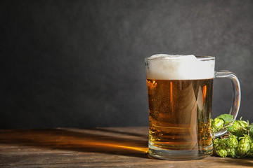 Composition with tasty beer and fresh green hops on wooden table. Space for text