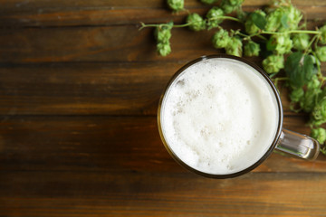 Flat lay composition with tasty beer, fresh green hops and space for text on wooden background