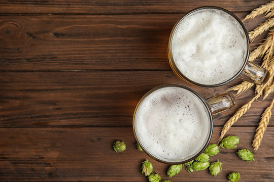 Flat lay composition with tasty beer and fresh green hops on wooden background. Space for text