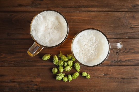 Flat lay composition with tasty beer and fresh green hops on wooden background