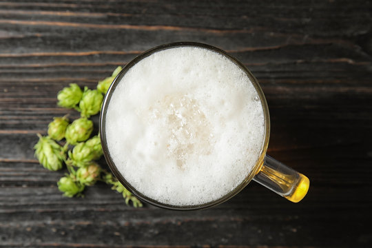 Flat lay composition with tasty beer and fresh green hops on wooden background