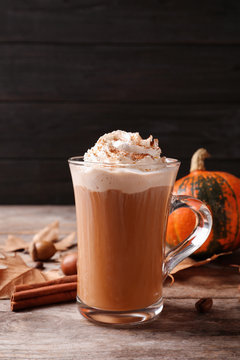 Glass cup with tasty pumpkin spice latte on wooden table