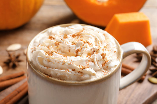 Cup with tasty pumpkin spice latte on table, closeup