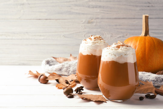 Fototapeta Glasses with tasty pumpkin spice latte on wooden table. Space for text