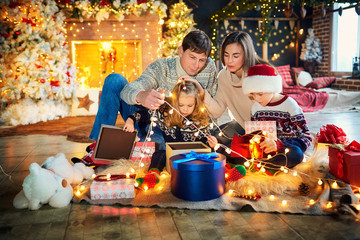 Family playing with gifts on the floor indoors on Christmas Day.