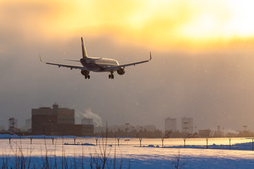 Fototapeta na wymiar On a snowy winter evening, a jet plane lands at Sheremetyevo Airport in Moscow, Russia