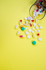 Disease concept. No to drugs and pills concept. Packaging of tablets and pills on the table. Pile of scattered capsules on yellow background.colorful capsules isolated, pharmacy bottle pill drug