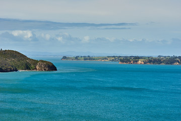 View of blue waters across a bay under a bright blue sky with some clouds